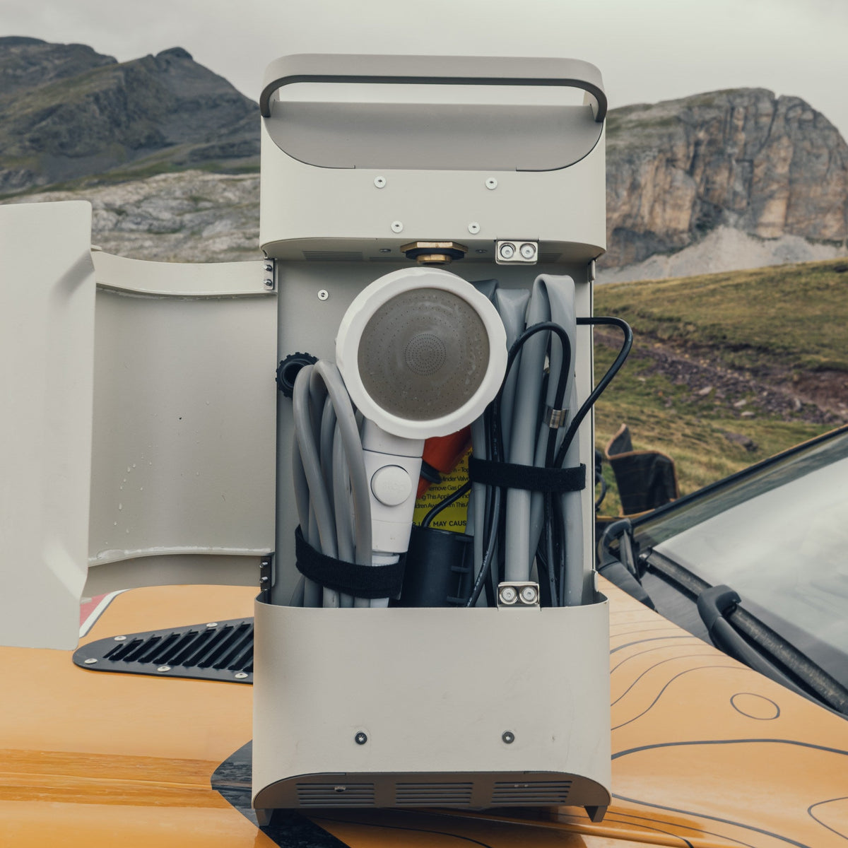 ThermoFlow with its storage compartment open, showing the shower head and hoses secured inside.