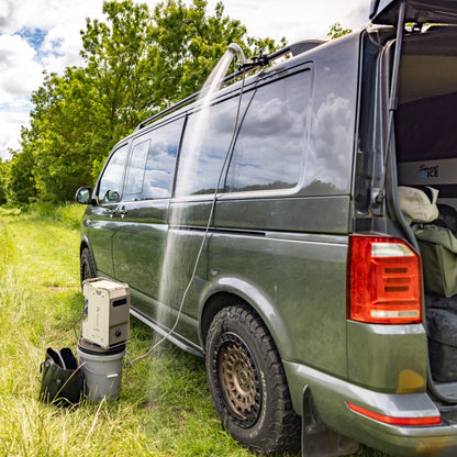 ThermoFlow beside a campervan, connected to a shower head with water running outdoors.