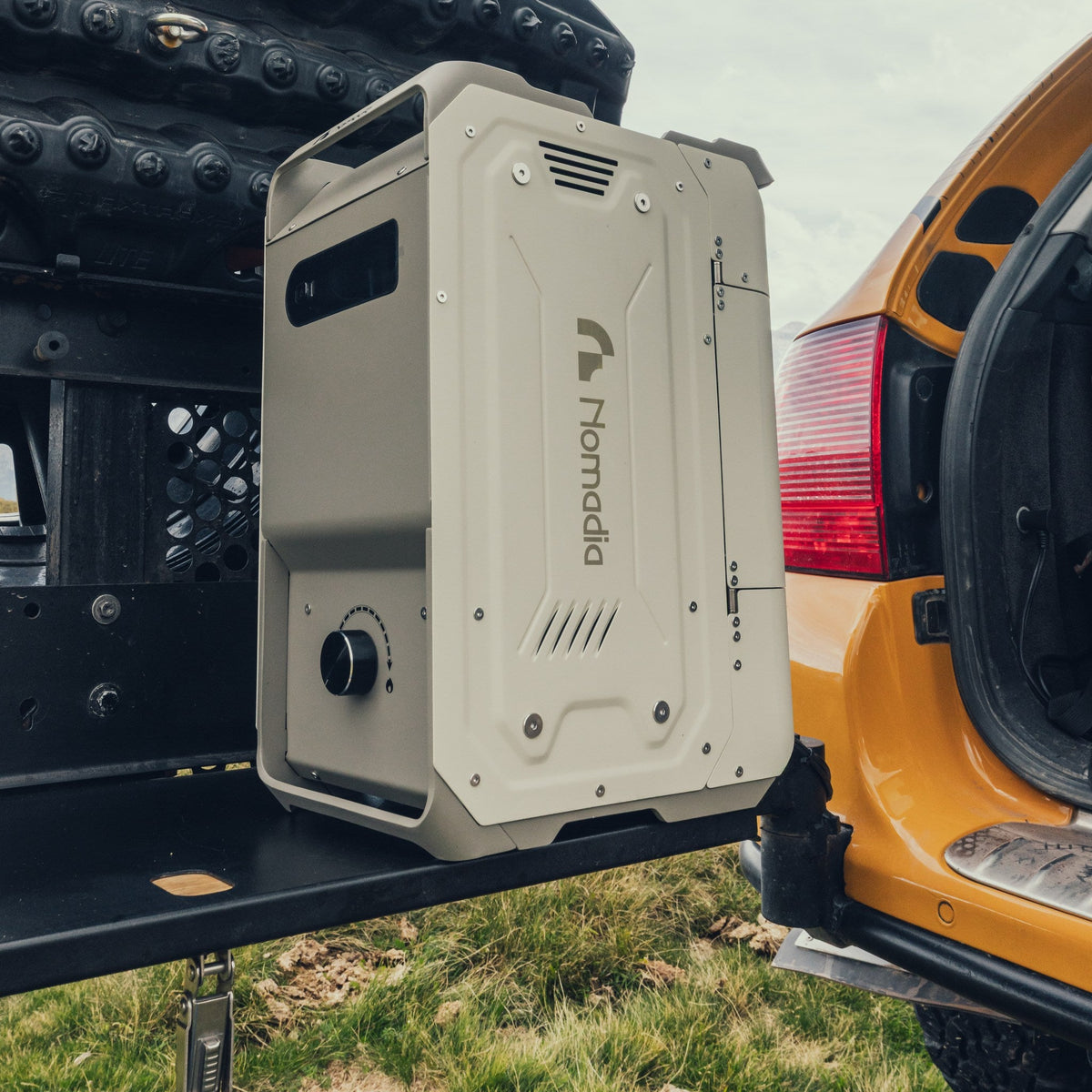 Front and side view of the Nomadia ThermoFlow portable hot water heater on a rear vehicle carrier.